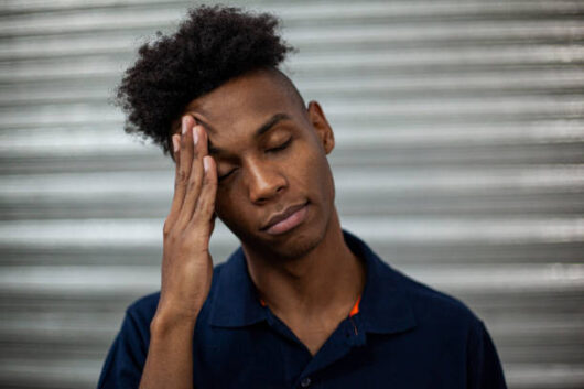 Young adult male operator having a heachache during daytime