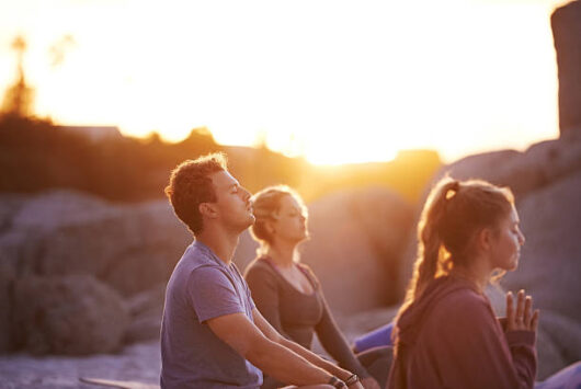 Shot of a group of people practising yoga on the beach